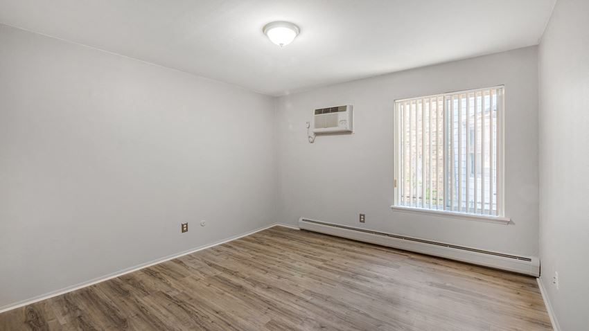 the living room of an empty house with wood flooring and a window