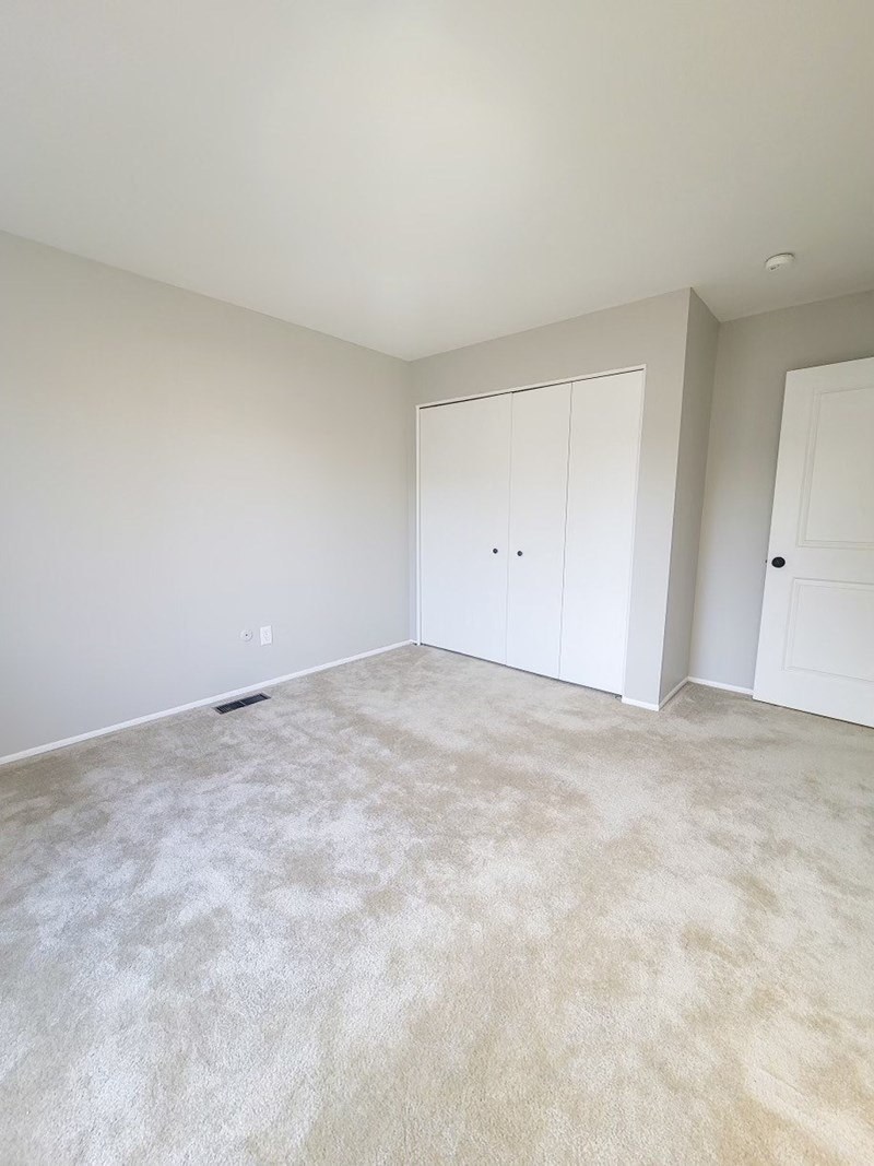 an empty living room with white walls and carpet