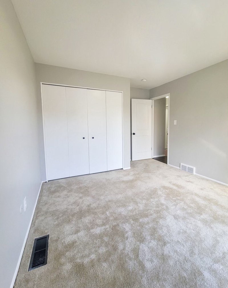 an empty living room with white walls and carpet