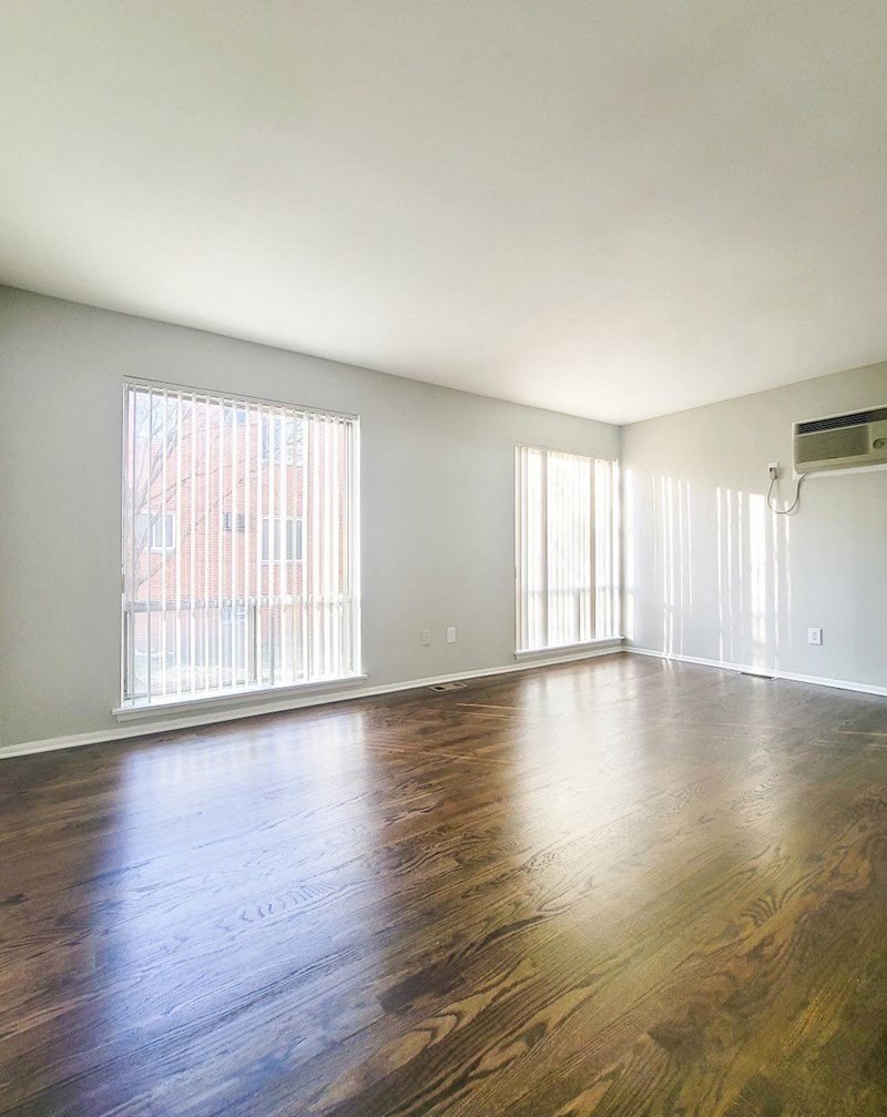 an empty living room with wood floors and a large window