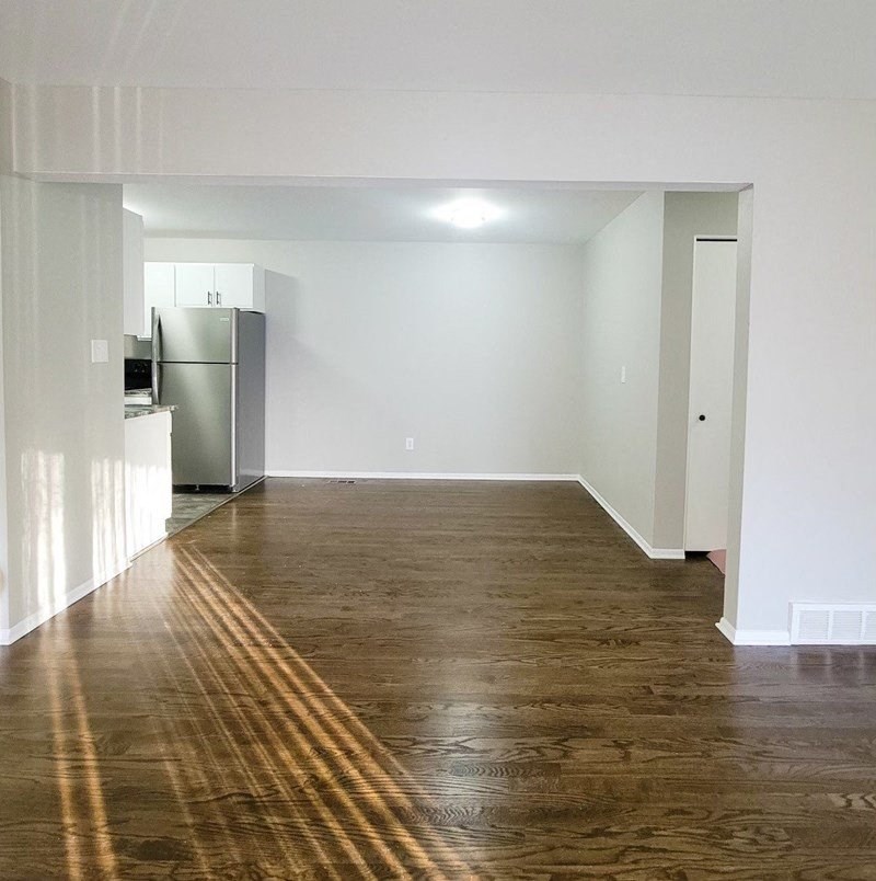 an empty living room and kitchen with a wood floor