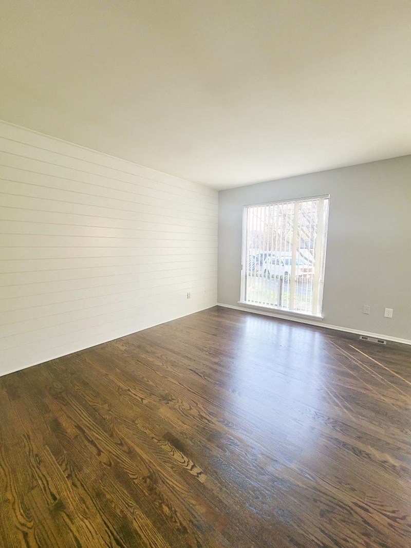 an empty living room with wood floors and a window