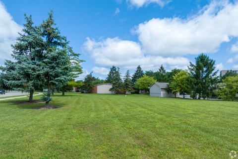 a large grassy field with houses in the background