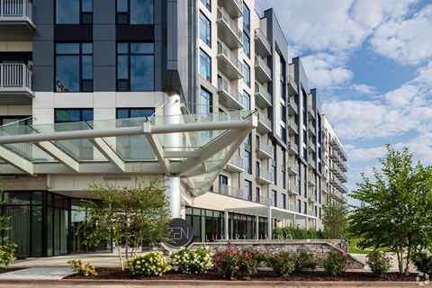 an apartment building with a large glass entrance and a courtyard with flowers