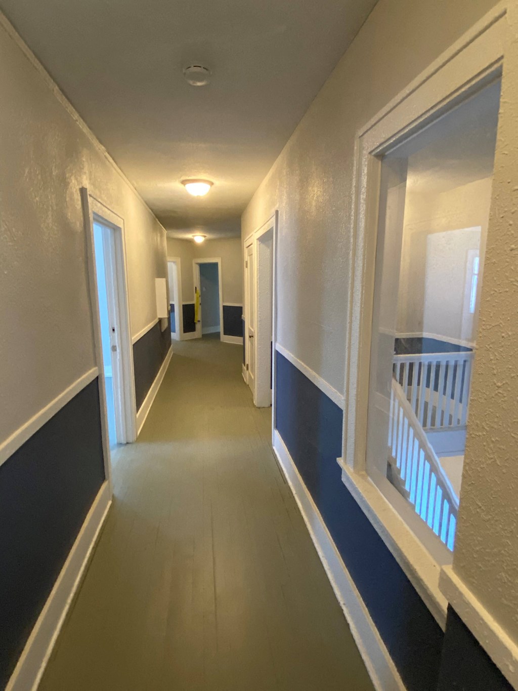 a hallway with a staircase and blue and white walls and a door and a window