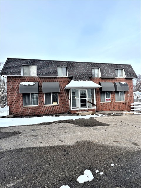 the front of a brick house with snow on the ground