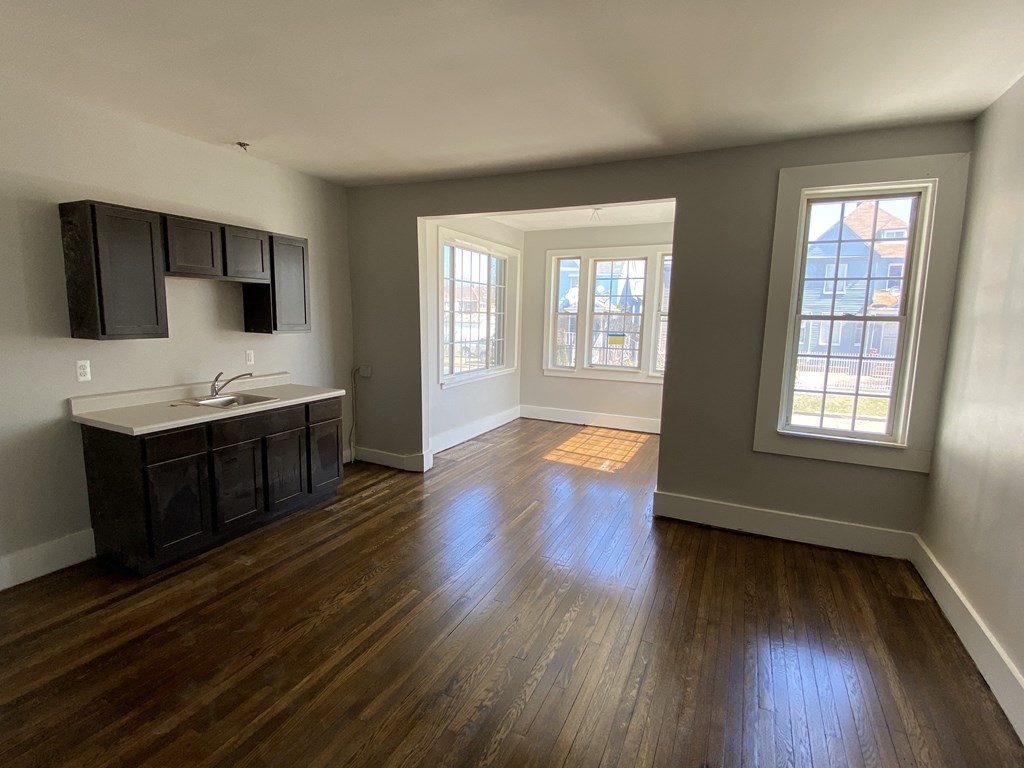 an empty living room with wood floors and a kitchen