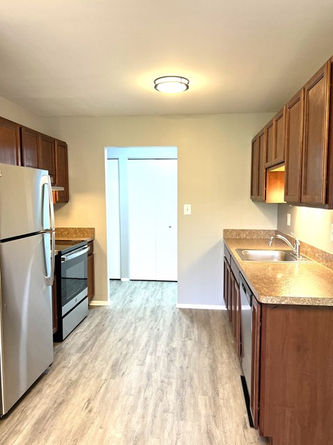 an empty kitchen with wooden cabinets and stainless steel appliances