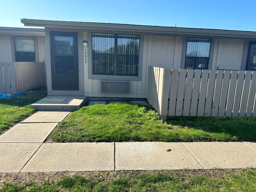 front of a mobile home with a white fence and grass
