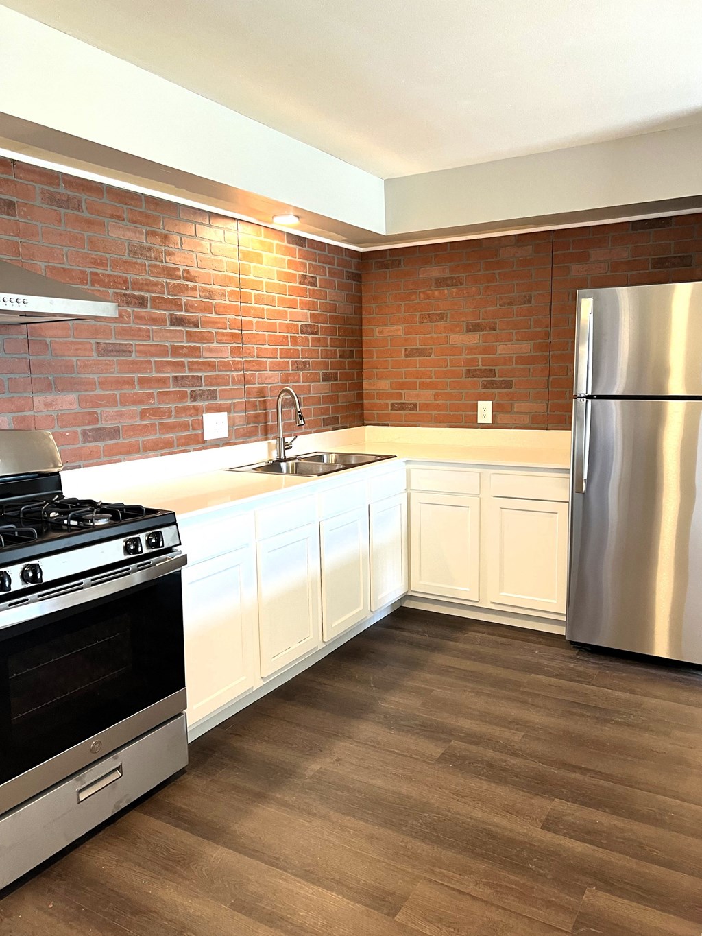 a kitchen with stainless steel appliances and a brick wall