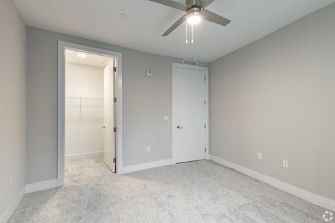 an empty room with a ceiling fan and a door to a closet