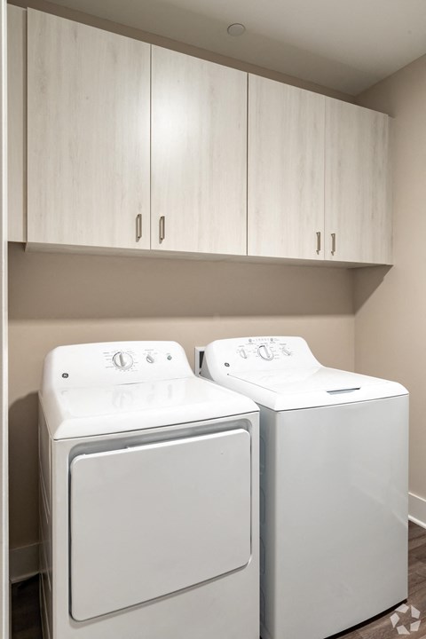 a washer and dryer in a laundry room with white cabinets