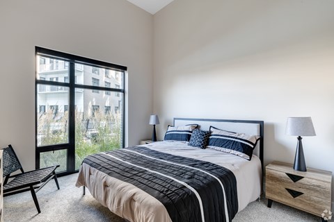 A bedroom with a large bed and a chair.