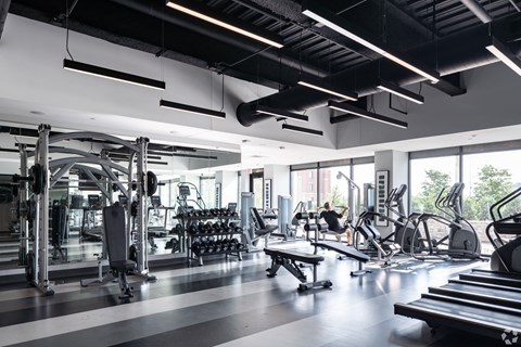 a gym with a lot of exercise equipment and large windows