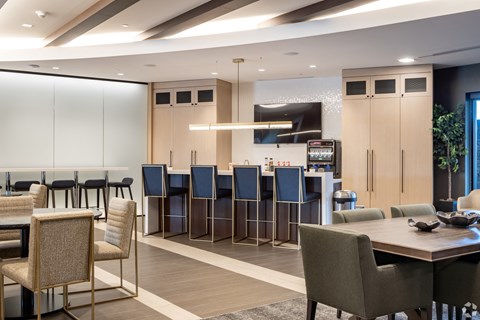 a communal table and chairs in a large room with a bar and chairs