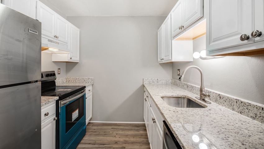 a kitchen with white cabinets and granite counter tops and stainless steel appliances