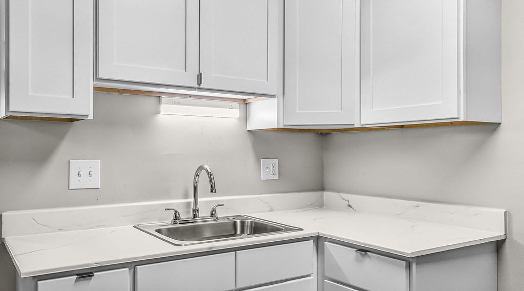 A kitchen with white cabinets and a sink.
