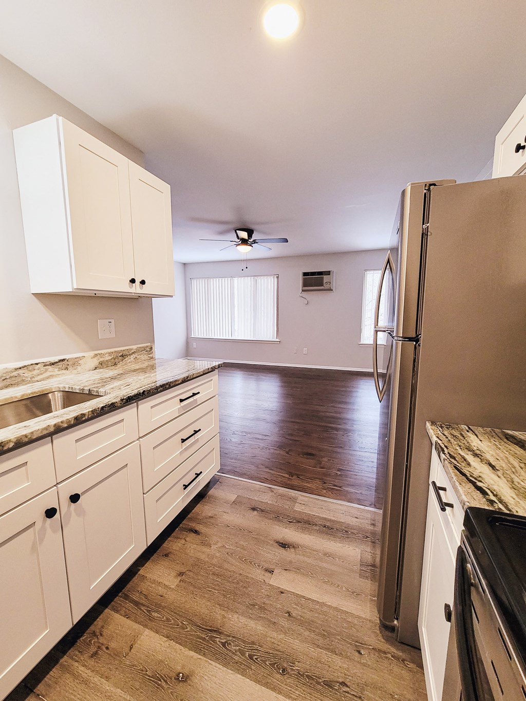 a kitchen with white cabinets and a hard wood floor and a refrigerator
