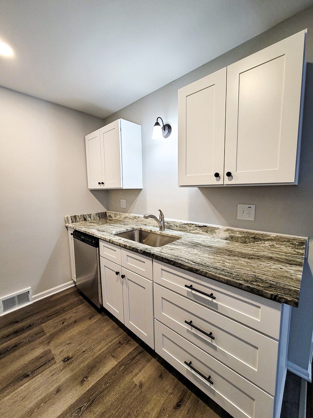 a kitchen with white cabinets and a counter top and a sink