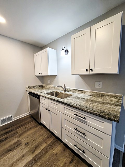 a kitchen with white cabinets and a counter top and a sink