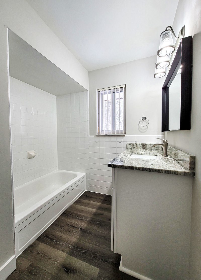 a white bathroom with a sink and a tub