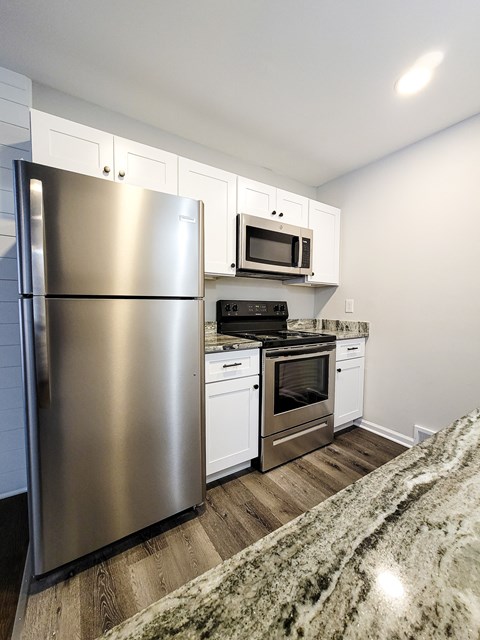A modern kitchen with a stainless steel refrigerator and white cabinets.