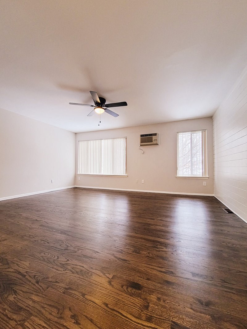 an empty living room with wood floors and a ceiling fan