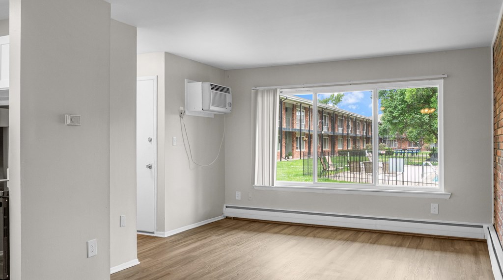 A room with a window showing a view of a residential area.