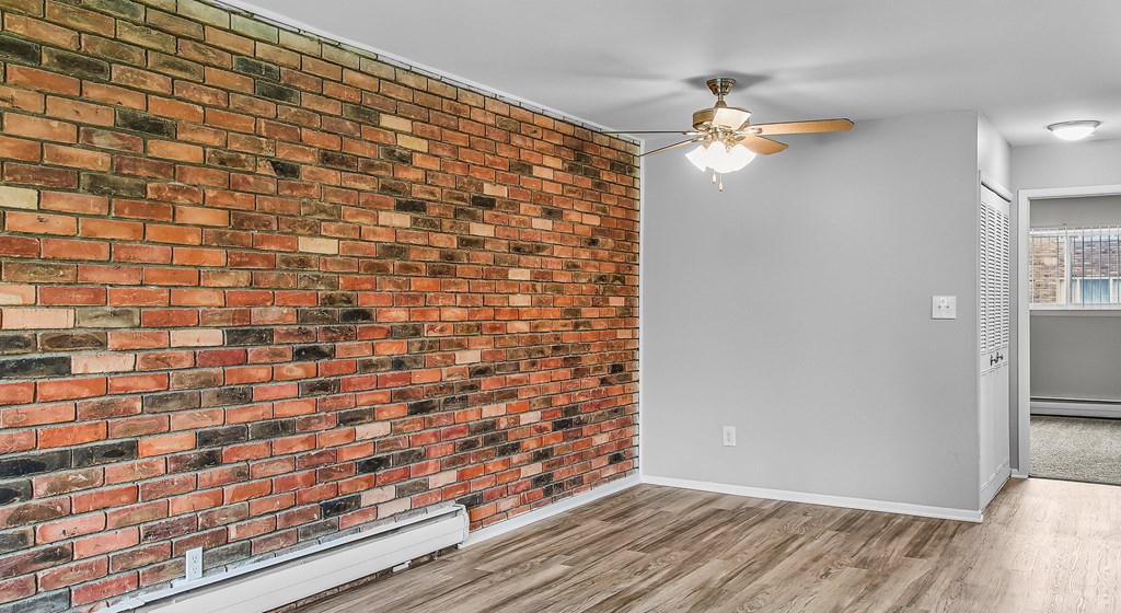 A room with a brick wall and a ceiling fan.