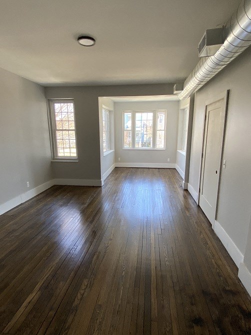 an empty living room with wooden floors and a window