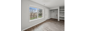 a living room with a large window and wooden floors