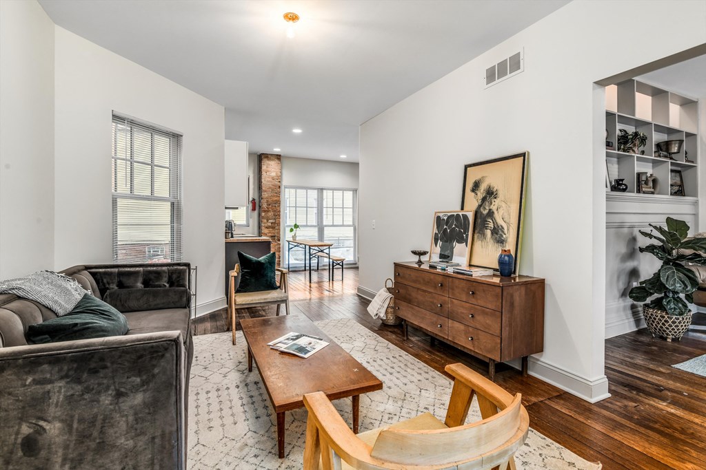 A living room with a grey couch, a wooden coffee table, and a painting on the wall.