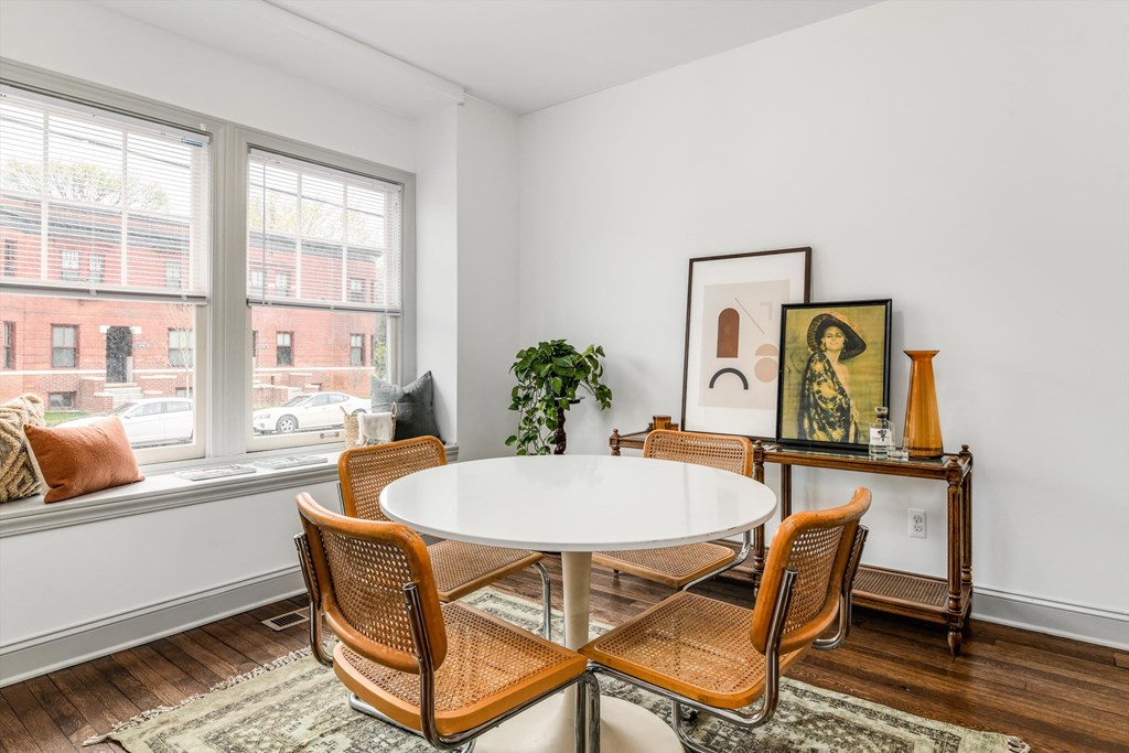 A white table with four chairs in front of a window.