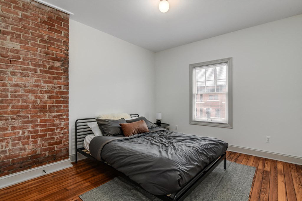A bedroom with a brick wall and a bed.