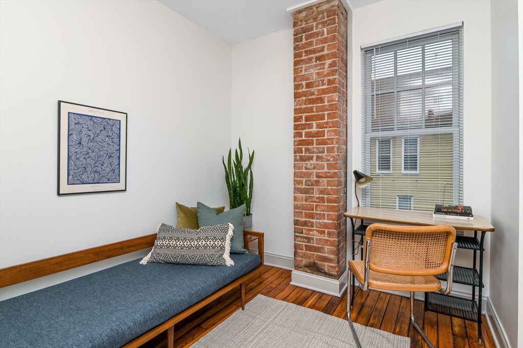 A room with a bed, a chair, and a painting on the wall.