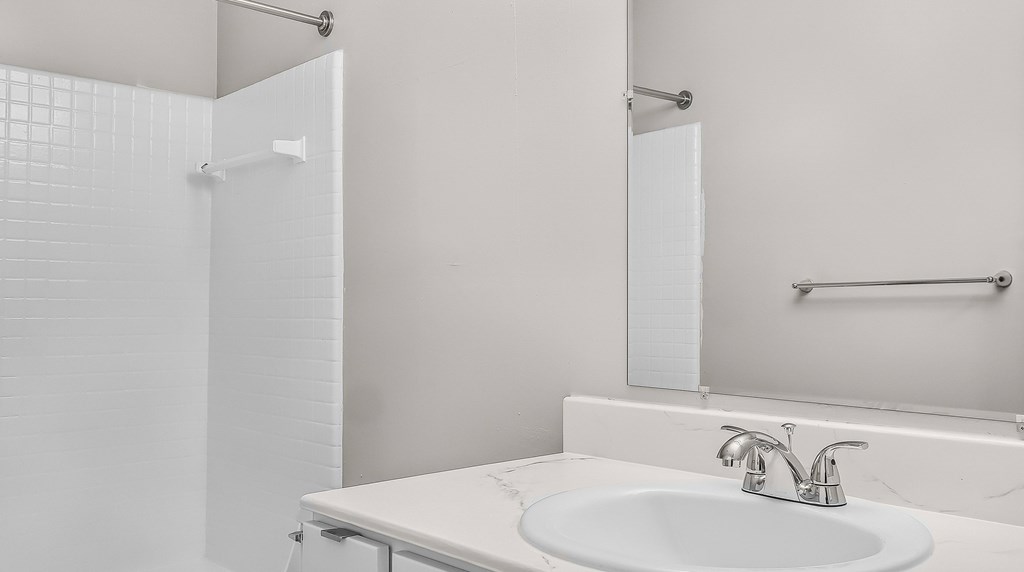 A white bathroom with a sink and a mirror.