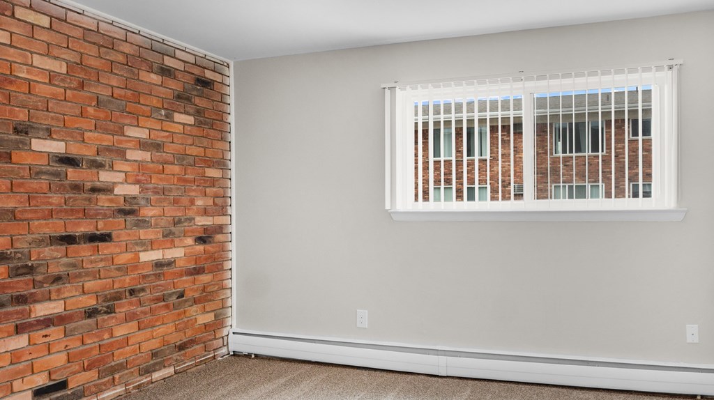 A room with a brick wall and a window with blinds.