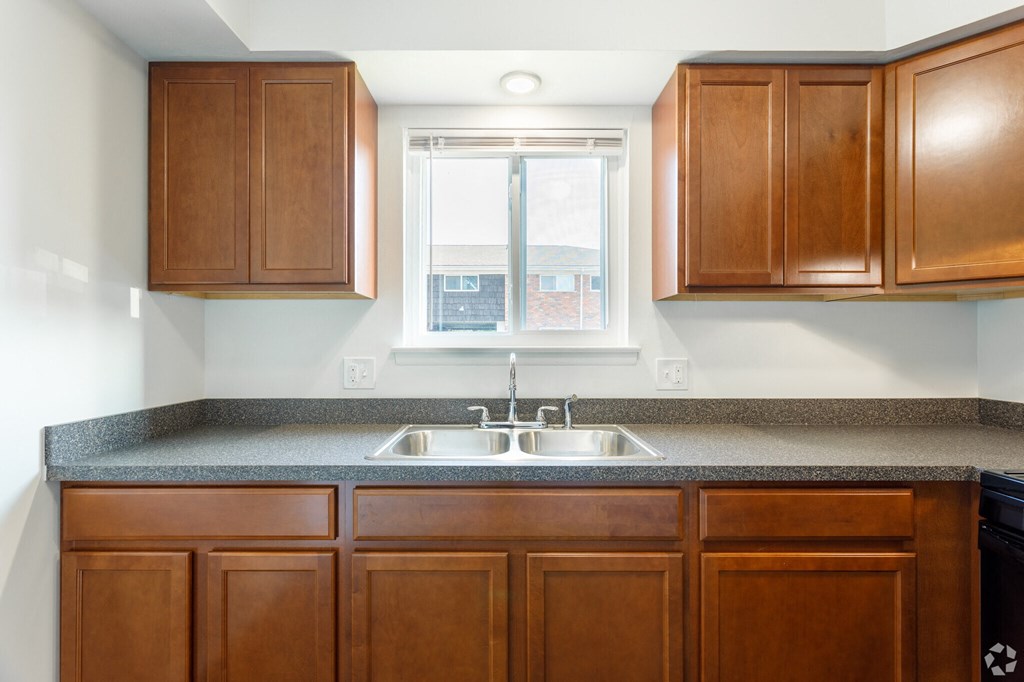 an empty kitchen with wooden cabinets and a window