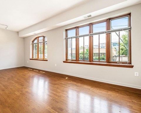 an empty living room with wood floors and large windows