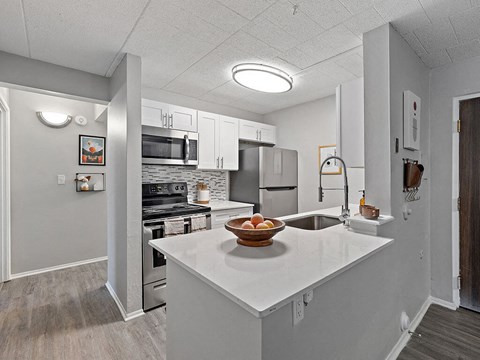 A kitchen with a white countertop and a bowl of fruit on it.