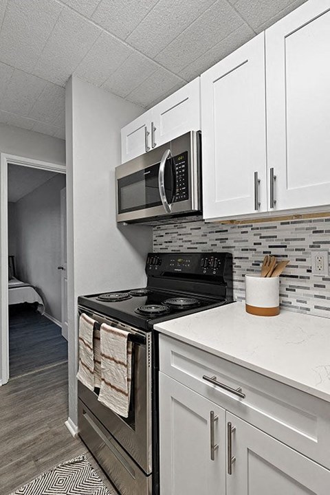A kitchen with a black stove top oven and a black microwave above it.