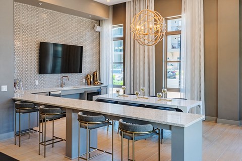 a kitchen with a counter and chairs and a tv