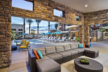 A patio with a pool and lounge chairs.