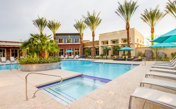 A pool surrounded by palm trees and lounge chairs.