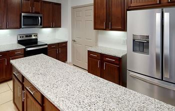 A kitchen with a granite countertop and stainless steel appliances.