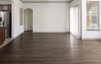 A spacious room with wooden flooring and white walls.