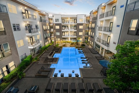 Resort-style pool area complete with sun shelf, lounge seating and fire feature