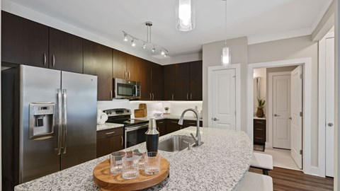 A modern kitchen with a refrigerator, microwave, and oven.