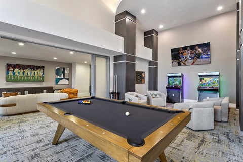 A pool table is in the middle of a room with a couch and a TV.