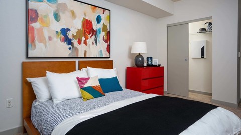 A bedroom with a large bed and a colorful painting above it.